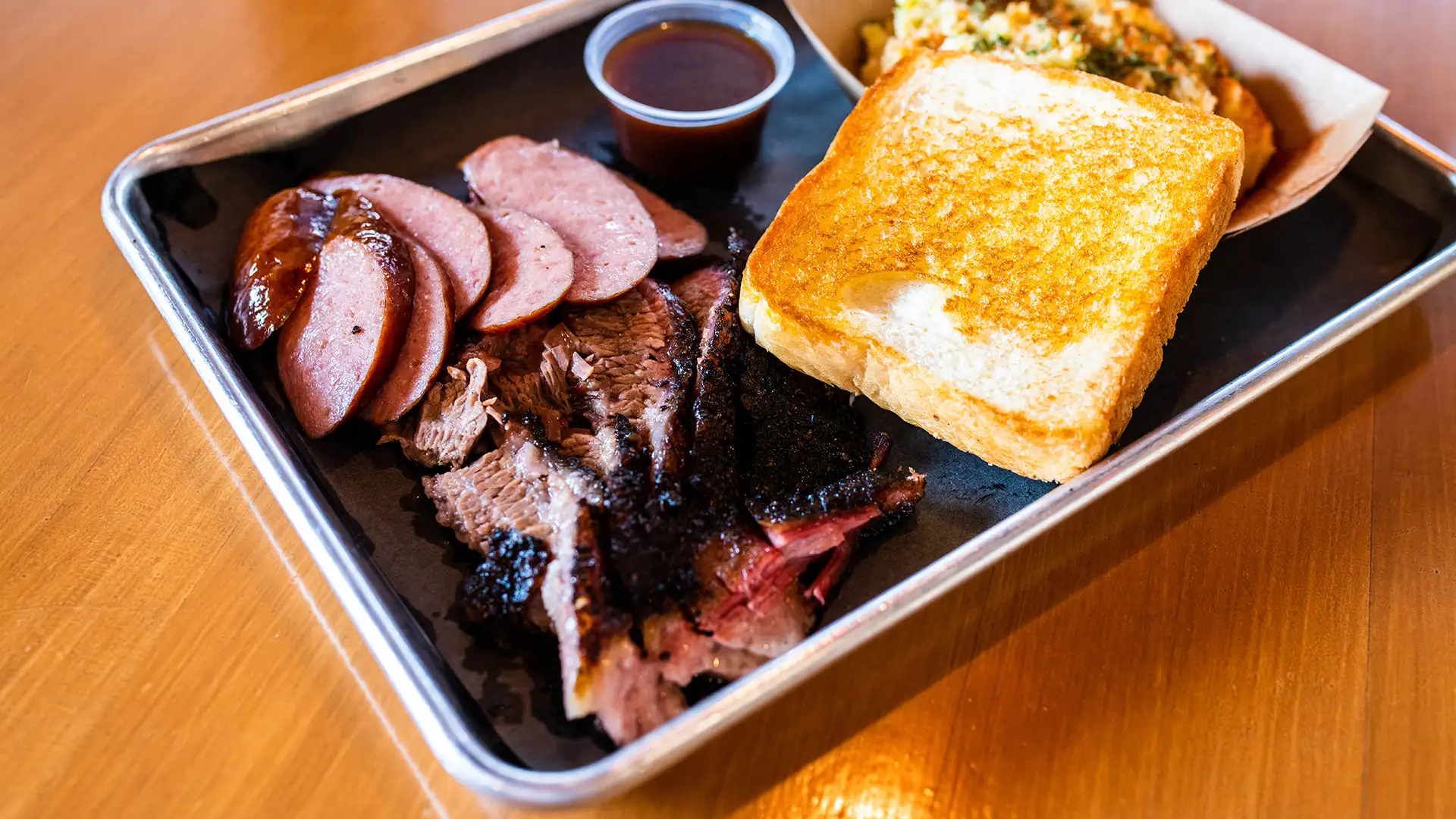 Plate with sausage, sliced brisket with a side of potato salad and toast
