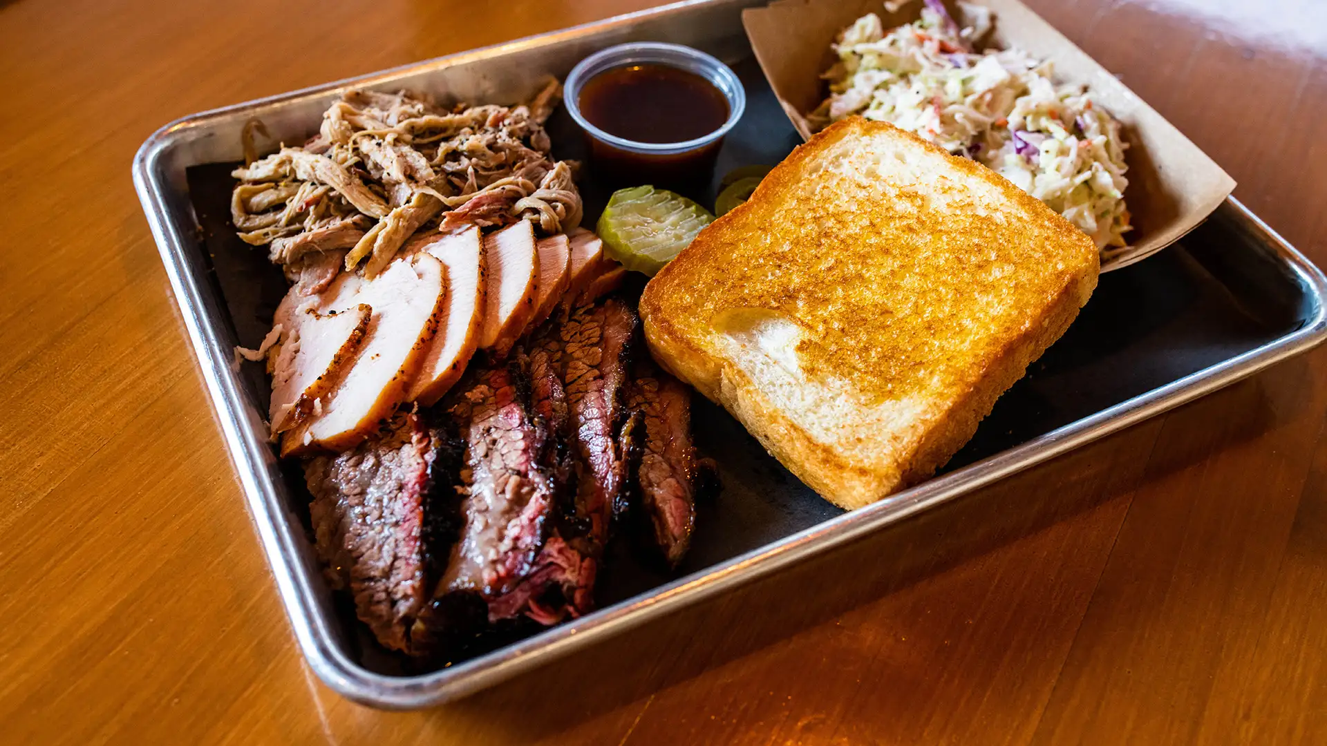 Plate with pulled pork, sliced turkey, sliced brisket with a side of coleslaw and toast